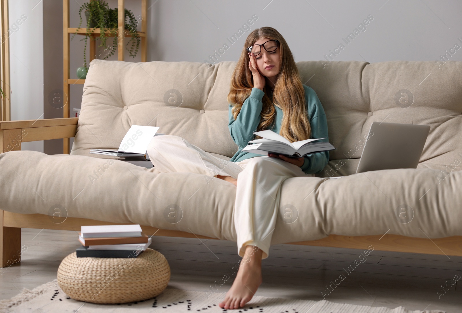 Photo of Young tired woman studying on couch at home