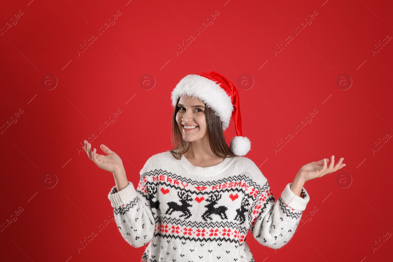 Photo of Pretty woman in Santa hat and Christmas sweater on red background