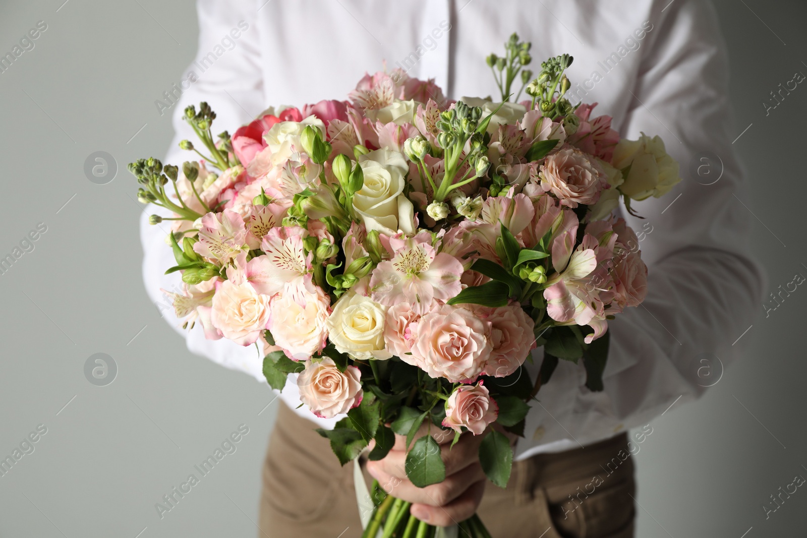 Photo of Man with beautiful bouquet of flowers on grey background, closeup