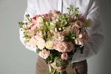 Photo of Man with beautiful bouquet of flowers on grey background, closeup