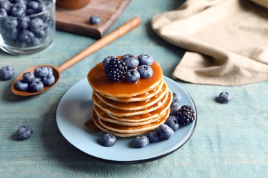 Tasty pancakes with berries and syrup on plate