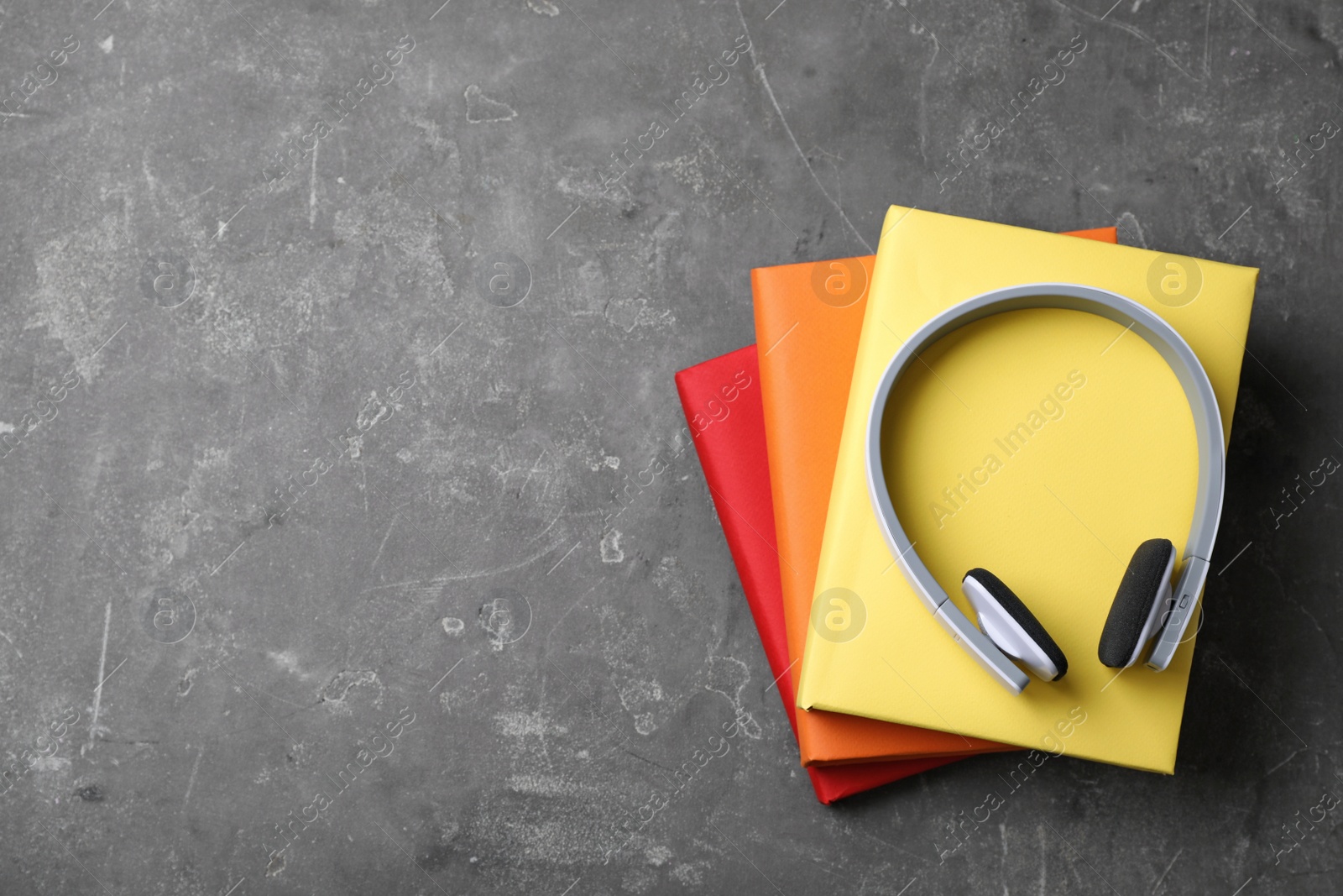 Photo of Modern headphones with hardcover books on grey background, top view. Space for text