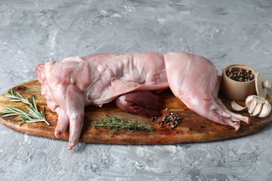 Photo of Whole raw rabbit, liver and spices on grey textured table