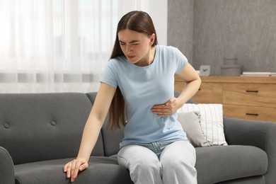 Woman having heart attack on sofa at home