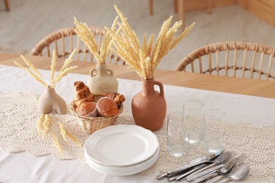 Photo of Clean dishes, dry spikes and fresh pastries on table in stylish dining room