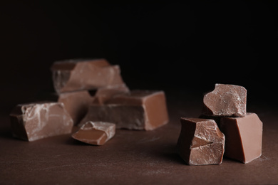 Pieces of milk chocolate on brown table