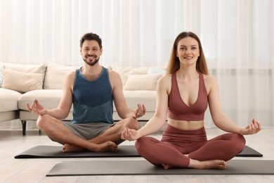 Couple in sportswear meditating together at home. Harmony and zen