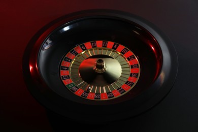 Photo of Roulette wheel with ball on black table, closeup. Casino game