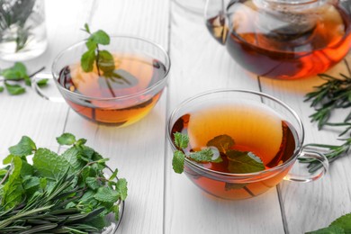 Photo of Aromatic herbal tea with mint and rosemary on white wooden table