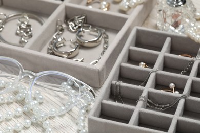 Photo of Jewelry boxes with many different accessories and glasses on white wooden table, closeup