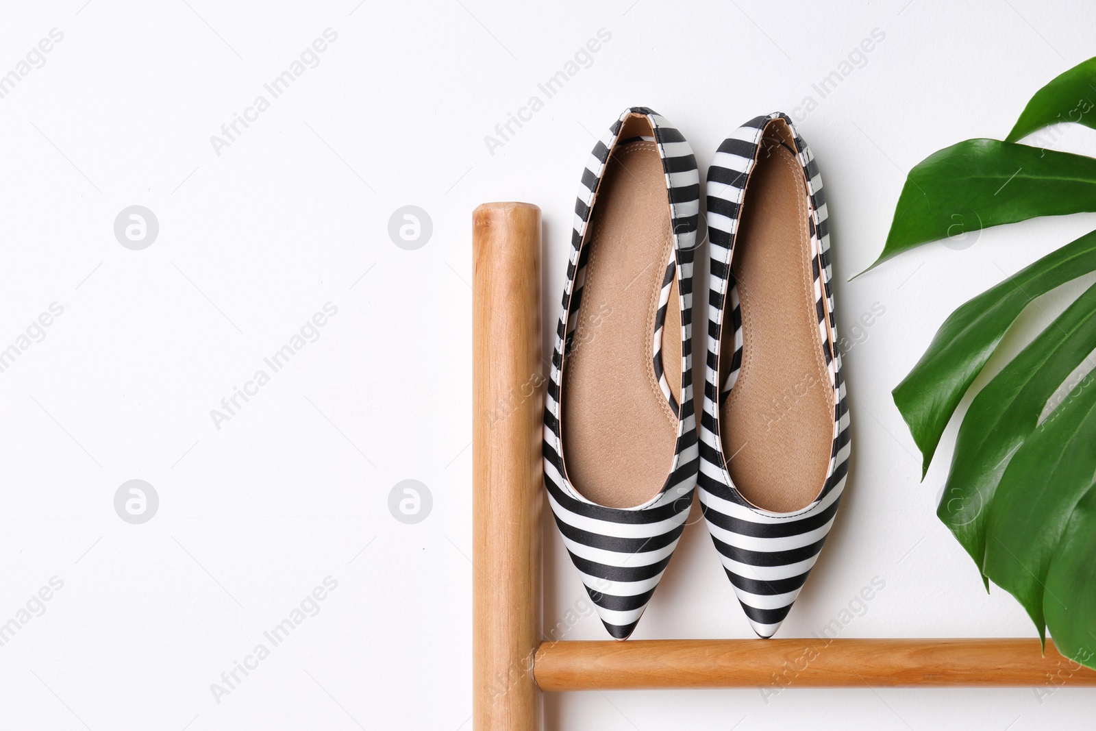 Photo of Pair of female shoes on wooden rail against white background