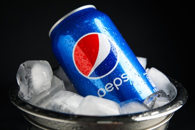 Photo of MYKOLAIV, UKRAINE - FEBRUARY 11, 2021: Can of Pepsi and ice cubes in bucket on black background, closeup