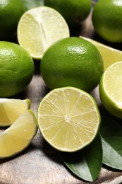 Photo of Fresh ripe limes and leaves on table, closeup