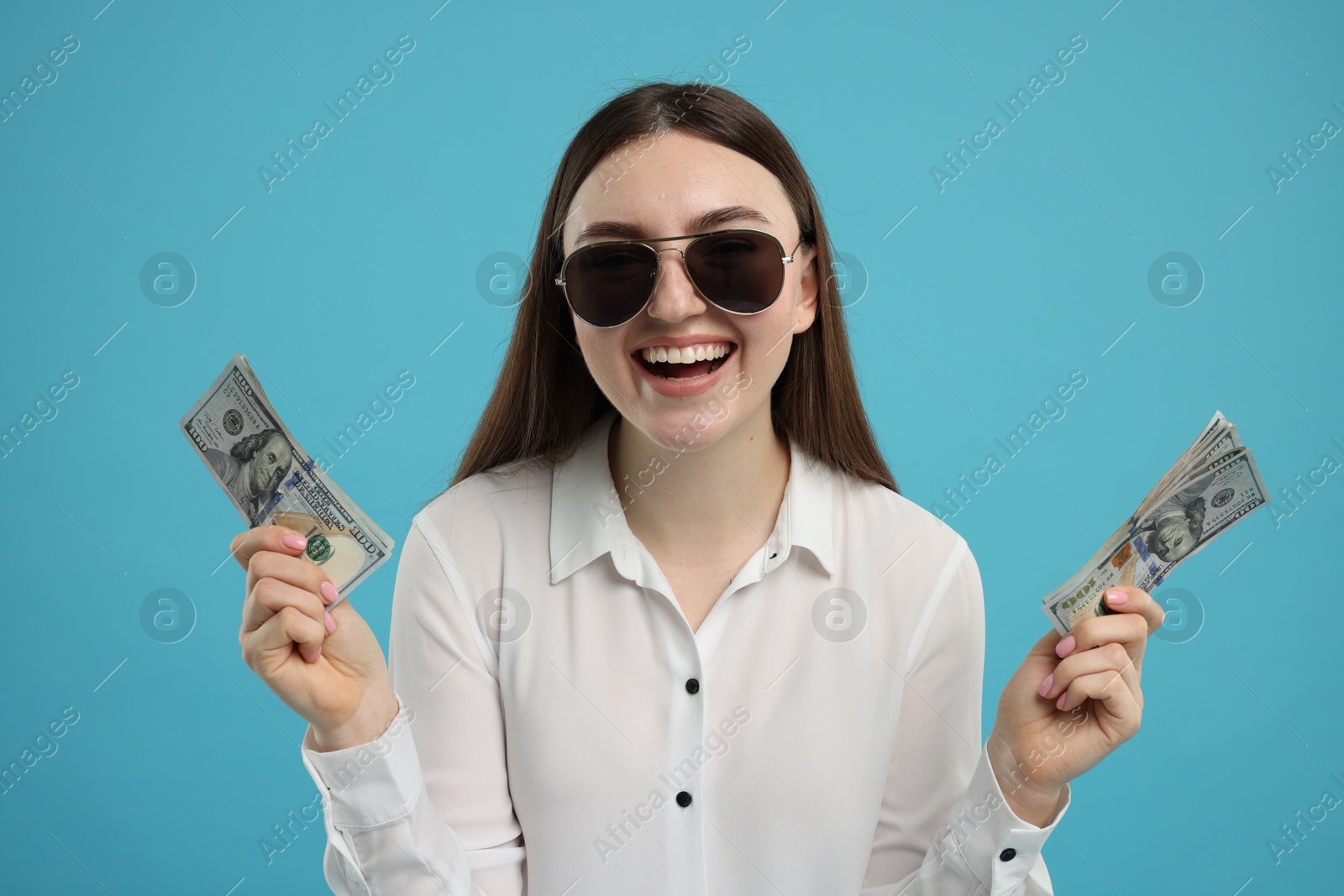 Photo of Happy woman with dollar banknotes on light blue background