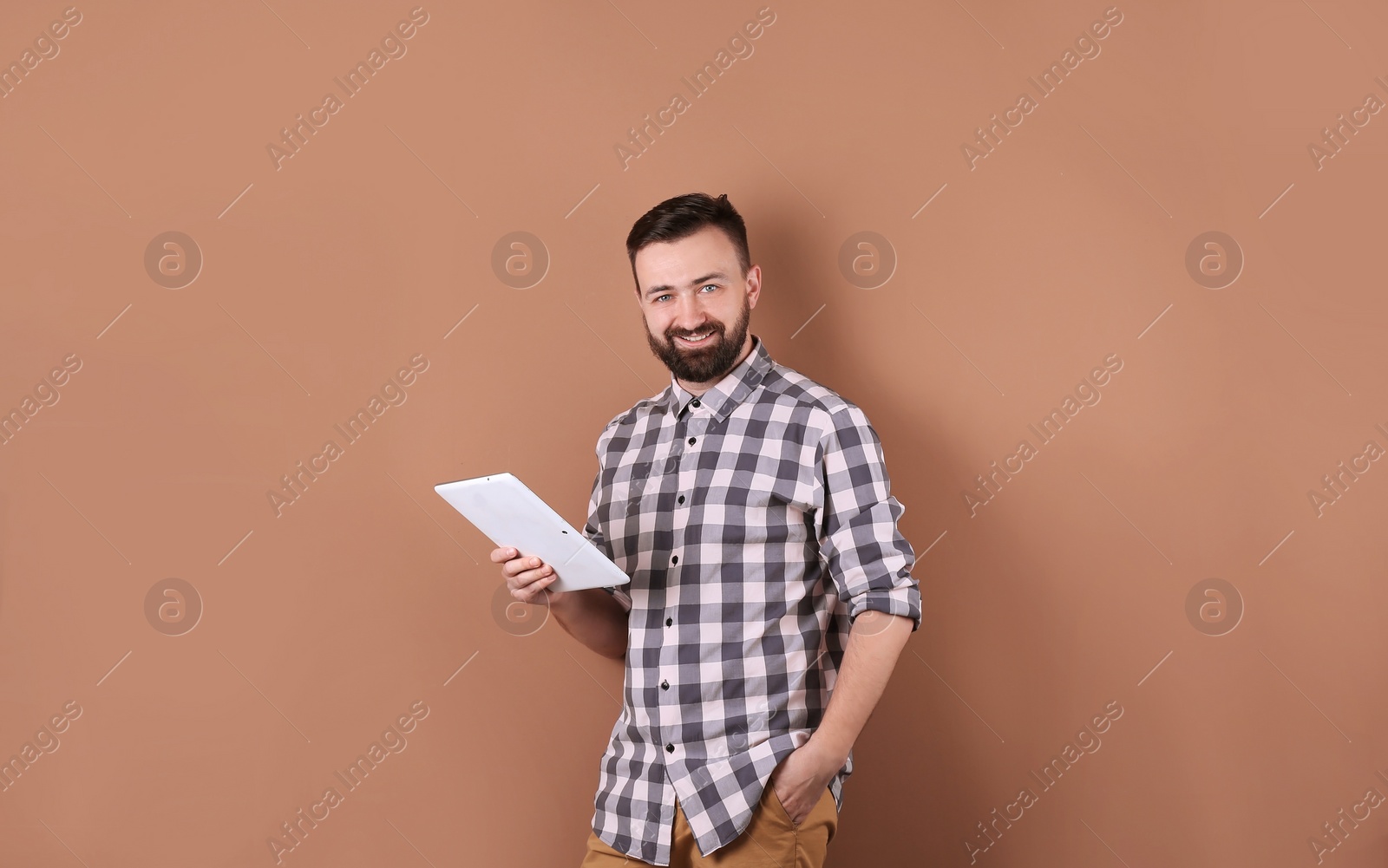 Photo of Portrait of handsome bearded man with tablet on color background