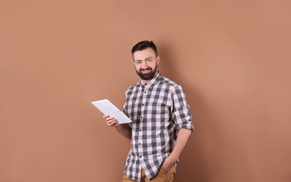 Portrait of handsome bearded man with tablet on color background