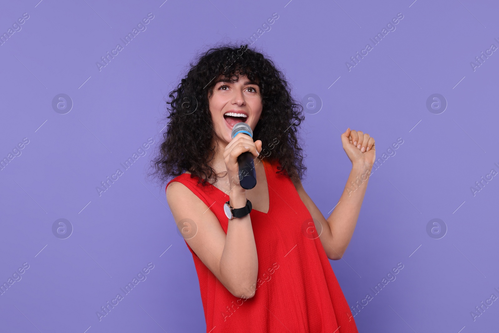 Photo of Beautiful young woman with microphone singing on purple background