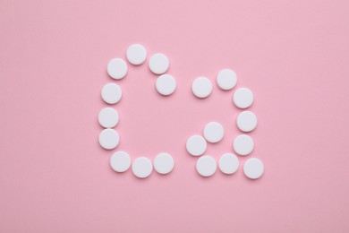 Calcium symbol made of white pills on pink background, flat lay