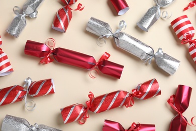 Photo of Red and silver Christmas crackers on beige background, flat lay