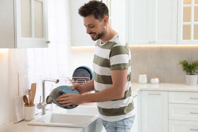 Photo of Man wiping plate with towel above sink in kitchen