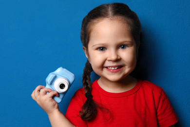 Photo of Little photographer with toy camera on blue background