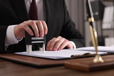 Notary stamping document at table in office, closeup