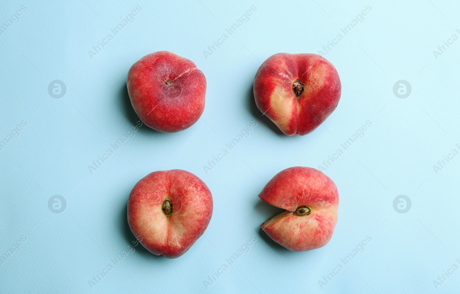 Photo of Fresh donut peaches on light blue background, flat lay