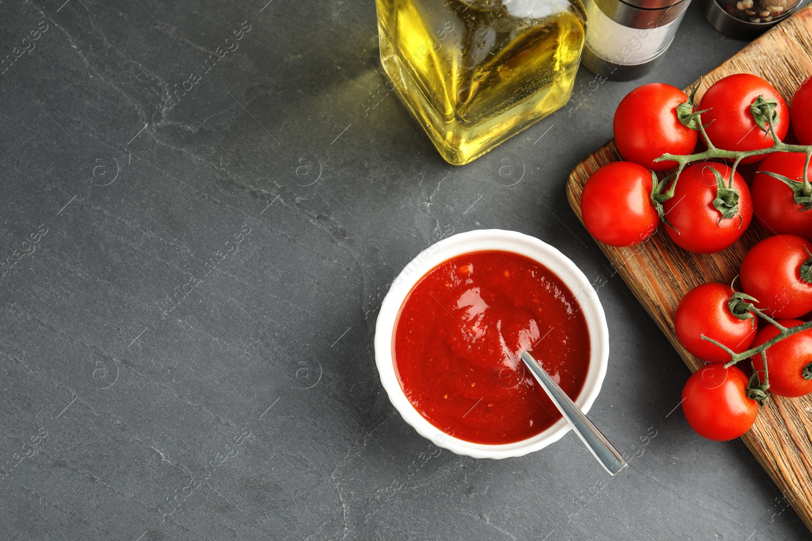Photo of Flat lay composition with bowl of sauce and tomatoes on grey table. Space for text