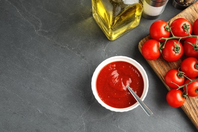 Flat lay composition with bowl of sauce and tomatoes on grey table. Space for text