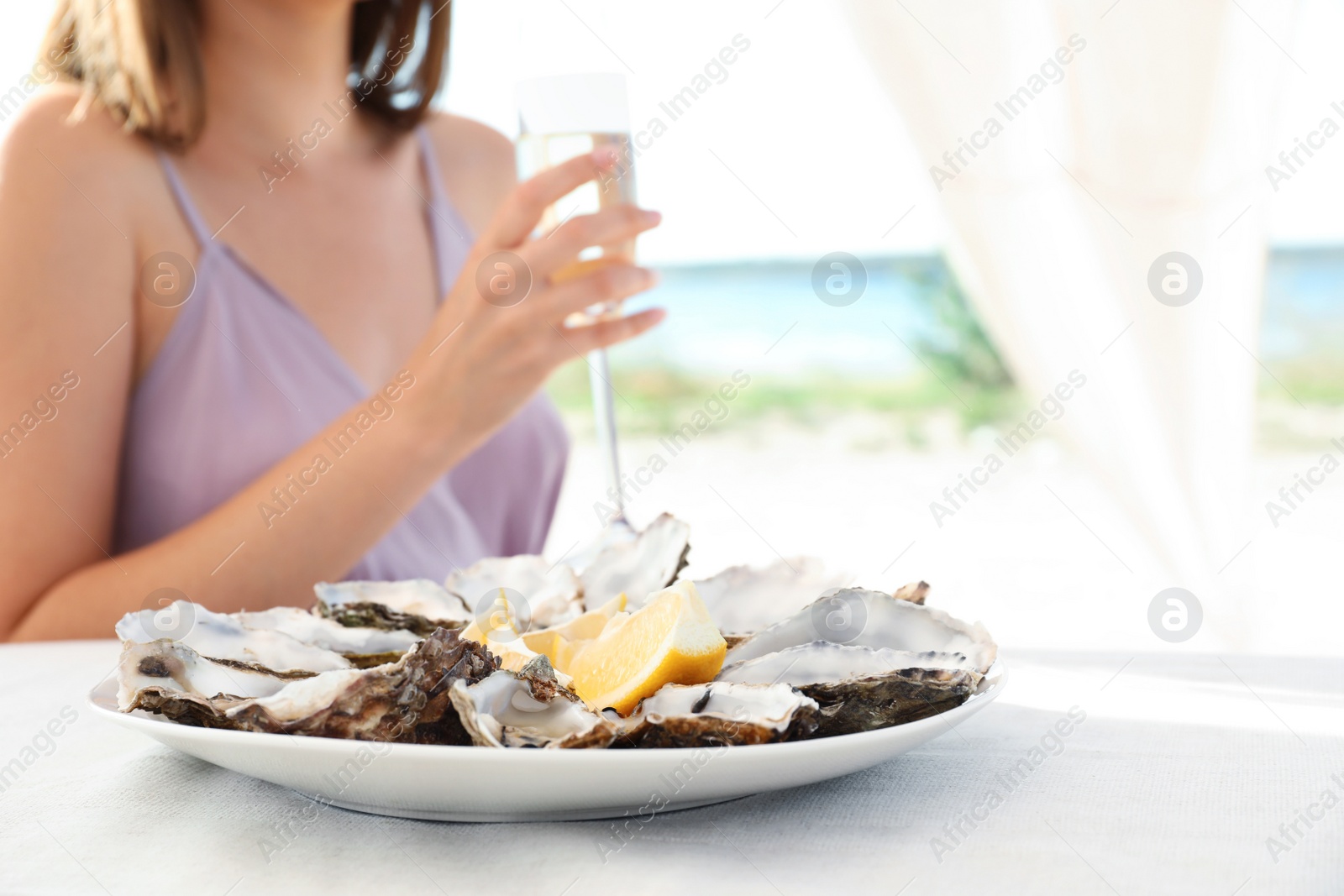 Photo of Woman with fresh oysters and glass of champagne at table