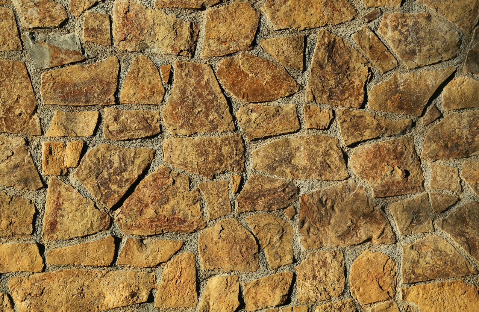 Photo of Texture of concrete wall decorated with stones as background, closeup