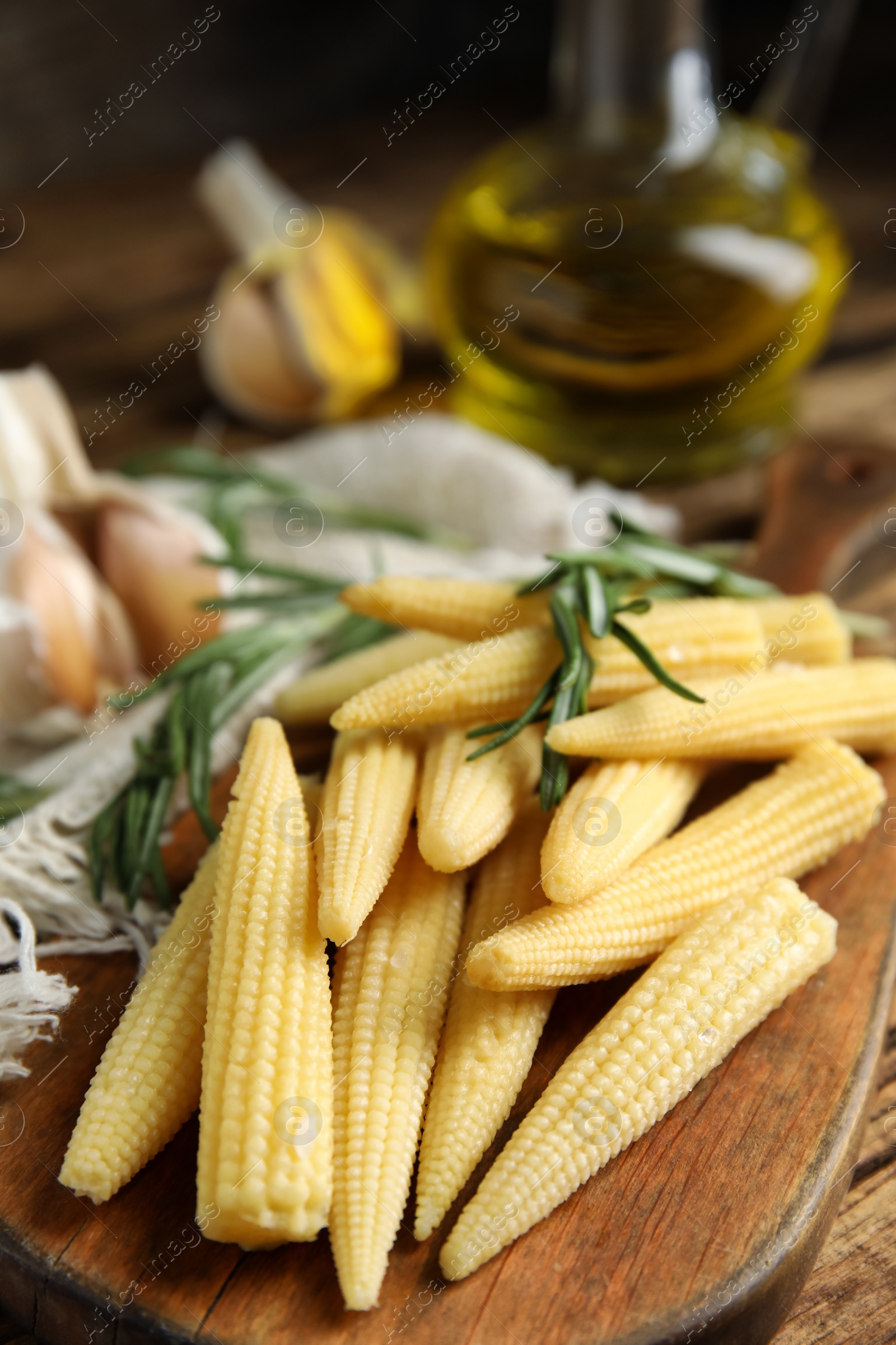 Photo of Fresh baby corn cobs on wooden board, closeup