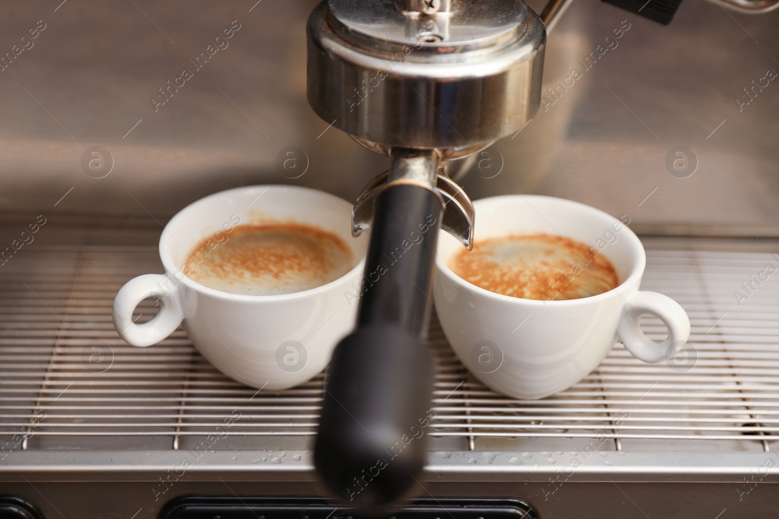 Photo of Coffee machine with cups on drip tray, closeup