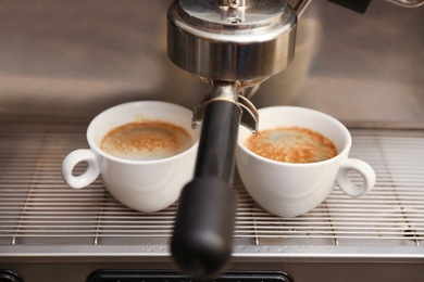 Coffee machine with cups on drip tray, closeup