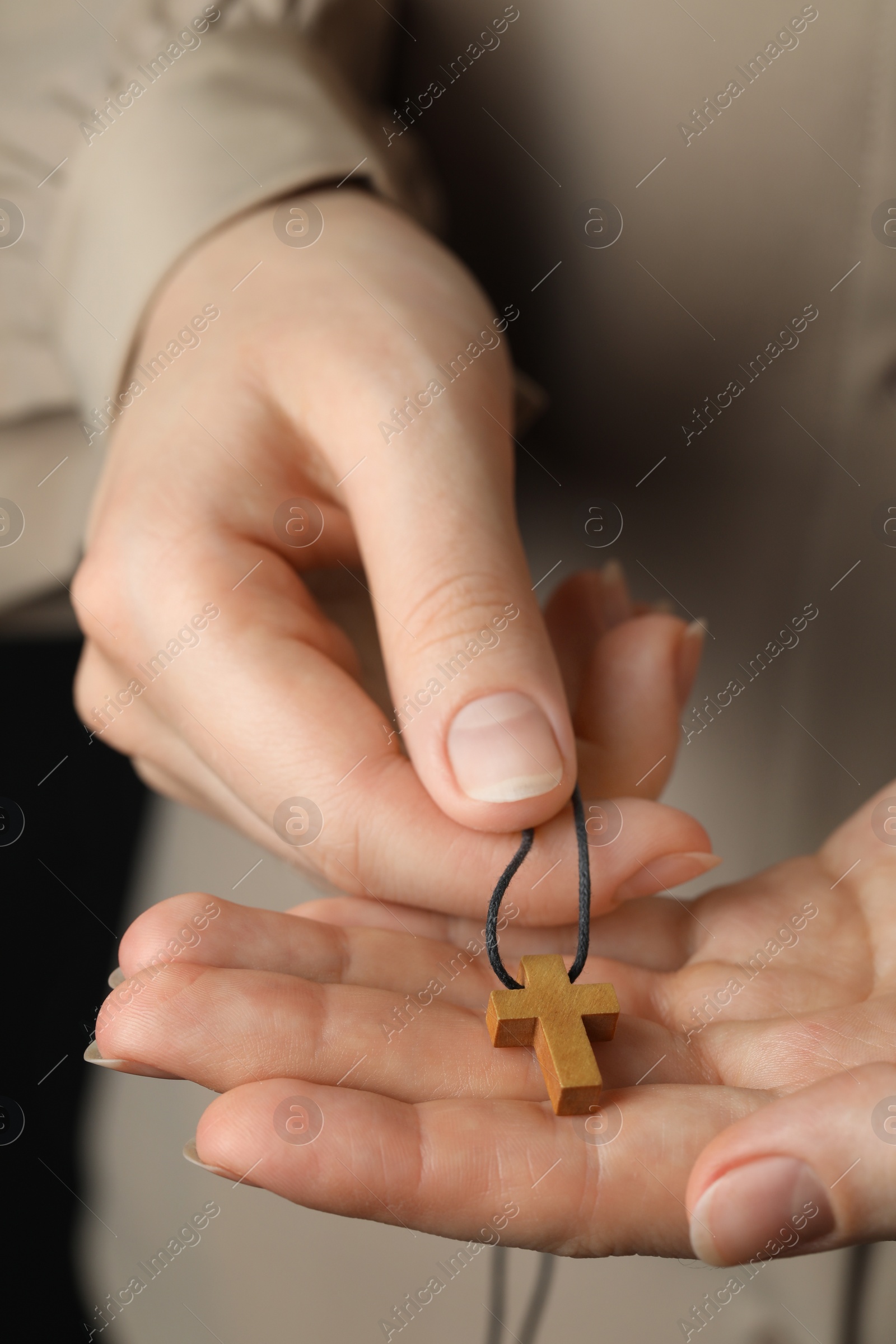 Photo of Woman holding wooden Christian cross, closeup view