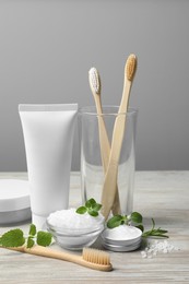 Photo of Toothbrushes, paste, green herbs and other teeth care products on wooden table