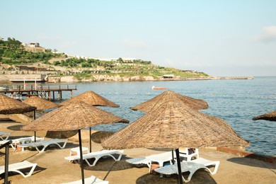 Photo of Lounge chairs and beach umbrellas on sea shore