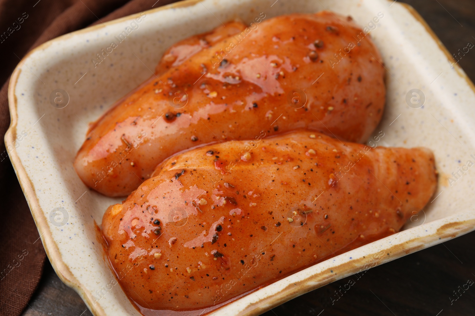 Photo of Raw marinated chicken fillets on wooden table, closeup