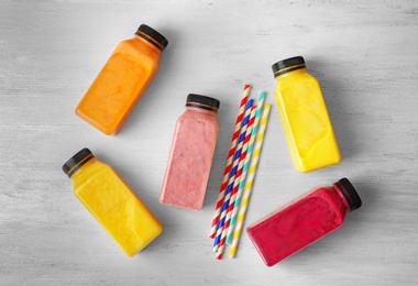 Bottles with delicious detox smoothies on wooden background, top view