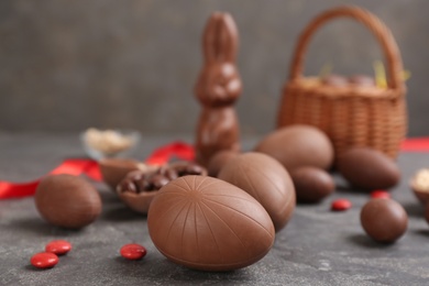 Photo of Sweet chocolate eggs and candies on grey table. Space for text