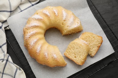 Delicious freshly baked sponge cake on black table, top view