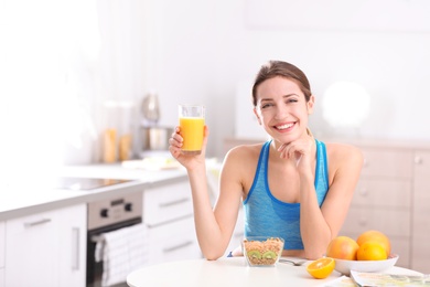 Photo of Young woman in fitness clothes having healthy breakfast at home