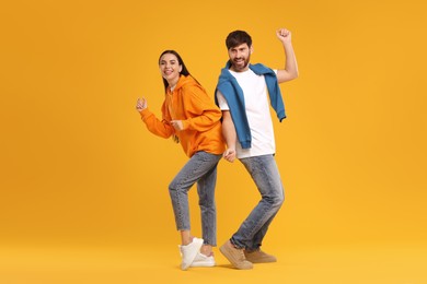 Happy couple dancing together on orange background