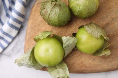 Photo of Fresh green tomatillos with husk on light table, top view
