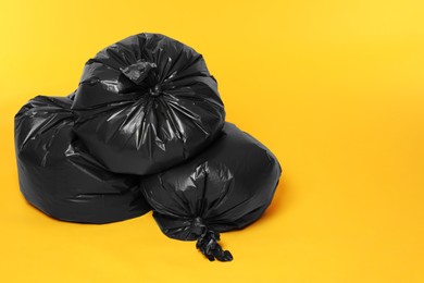 Photo of Trash bags full of garbage on orange background. Space for text