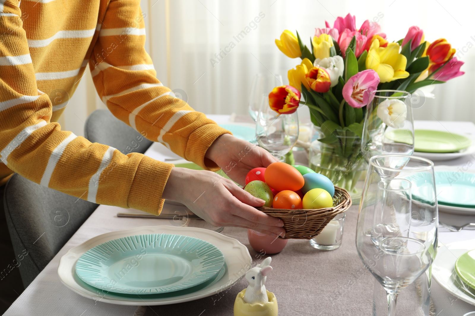 Photo of Woman setting table for festive Easter dinner at home, closeup