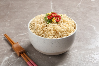 Bowl of noodles with vegetables and chopsticks served on table