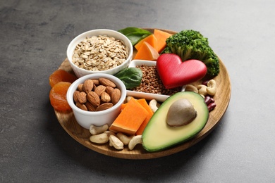 Wooden plate with heart-healthy products on grey background