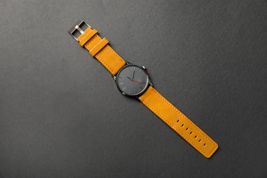 Photo of Stylish wrist watch on dark background, top view. Fashion accessory