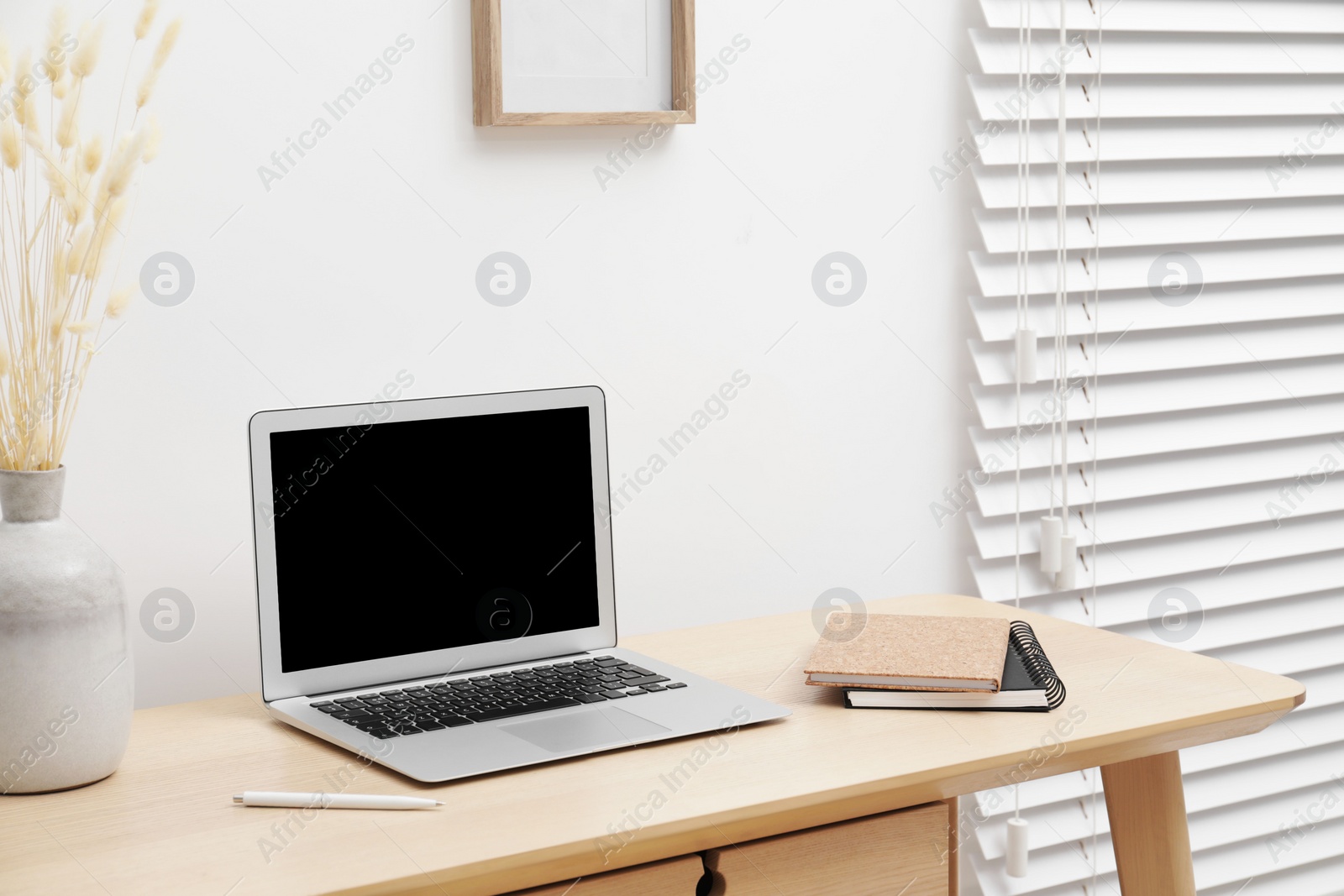 Photo of Cosy workspace with laptop and stationery on desk at home